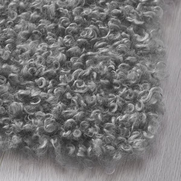 Fluffy grey rug, soft texture, placed on wooden floor, showcasing quality and comfort.