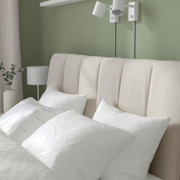Modern TÄLLÅSEN bed with soft headboard, adjustable sides, flowers, and lamps.