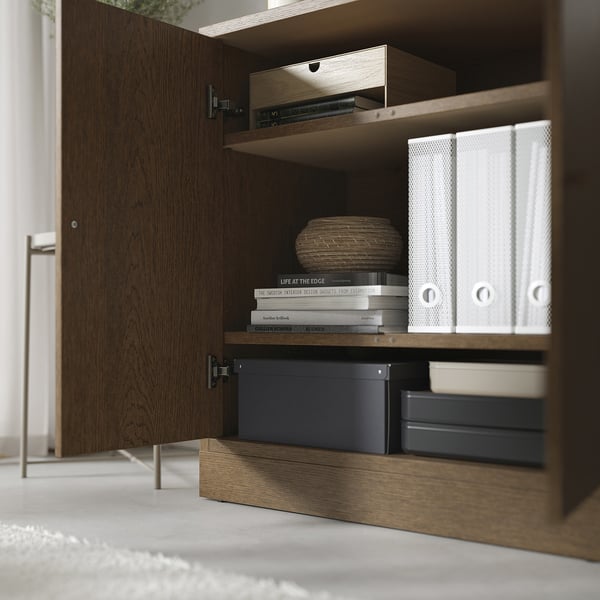 Wooden cabinet with multiple shelves storing books, binders, and boxes. Adjustable shelves provide customizable storage.