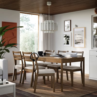 Dining table with six chairs, oak, cushioned, plant, artwork.