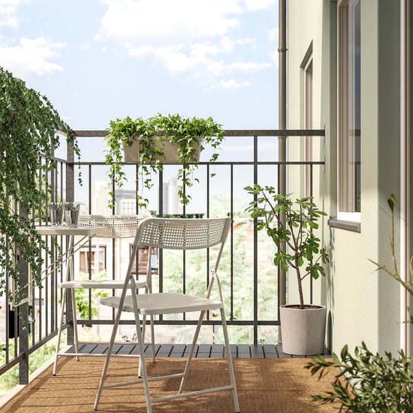 Balcony setup with white TORPARÖ table & chairs, green plants. Compact, modern design.