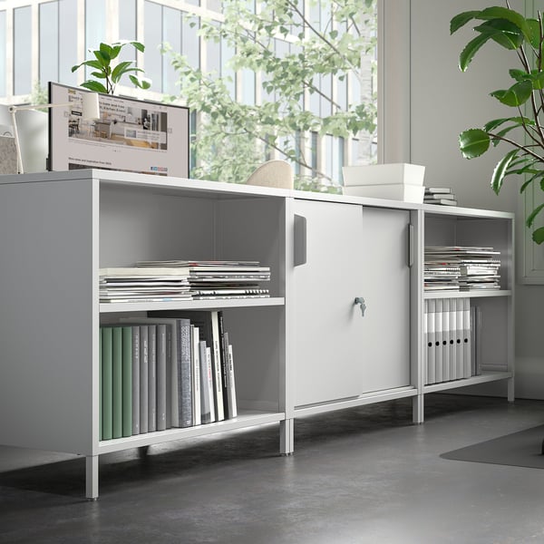 A sleek, white trottén double-sided cabinet with adjustable shelves, ideal for room division.