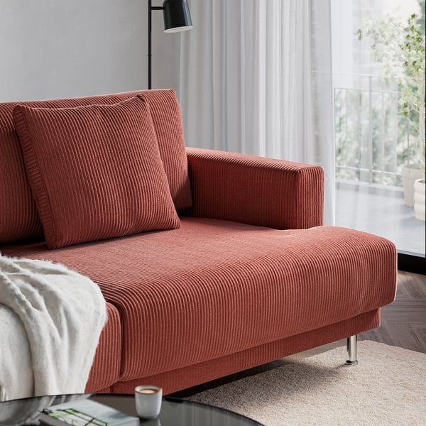 Orange UPPÅKRA sofa, oversized cushions, near window with lamp.