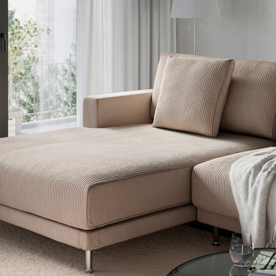 L-shaped sofa with beige striped fabric, large cushions, and metal legs, in a bright living space.