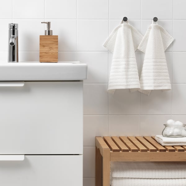 Modern bathroom with VÅGSJÖN towels on hooks, wooden shelf with folded towels, soap dispenser. Clean, minimalist design.