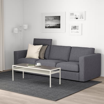 Modern living room with black VIMLE sofa, grey cushions, white coffee table, black patterned rug, lamp, and wall decor.