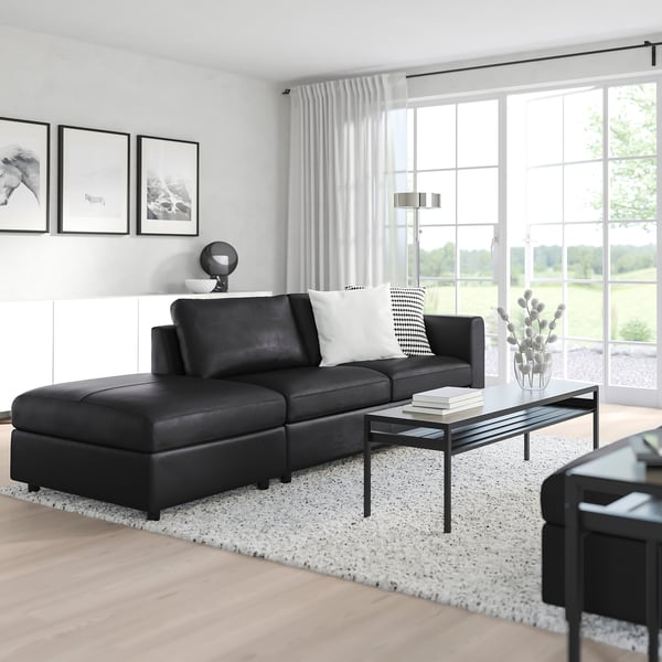 Black VIMLE sectional sofa with storage footrest, throw pillows, coffee table, large windows & rug.