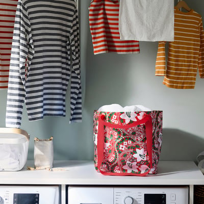 White shelf with VINTERFINT red, floral-patterned carrier, smaller than hanging striped clothes.