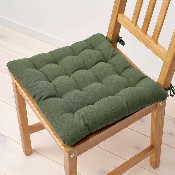 Green tufted chair pad on wooden chair. Thick, cushioned, with ties to secure.