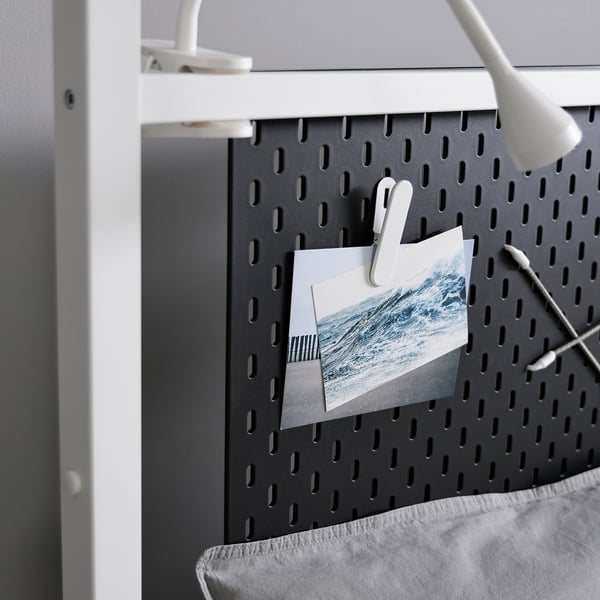 Black pegboard with white clips and waves, mounted on white frame.
