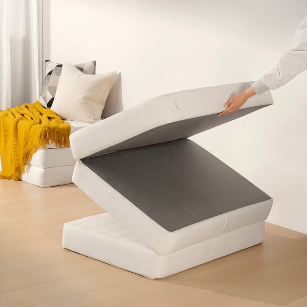 Person lifting ottoman lid revealing storage space.