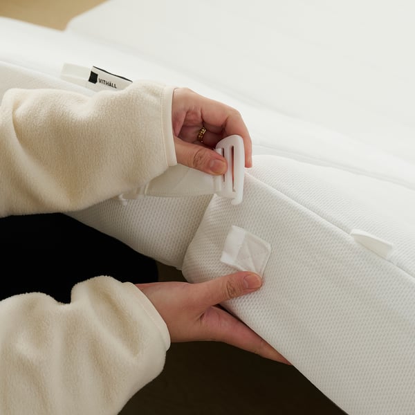 Person unfold bed mattress using handles.