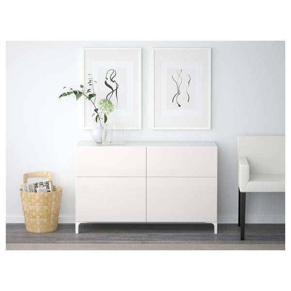 Minimalist sideboard with drawers and doors, elevating design, soft-close feature. Art and vases displayed on top, wicker magazine basket beside.