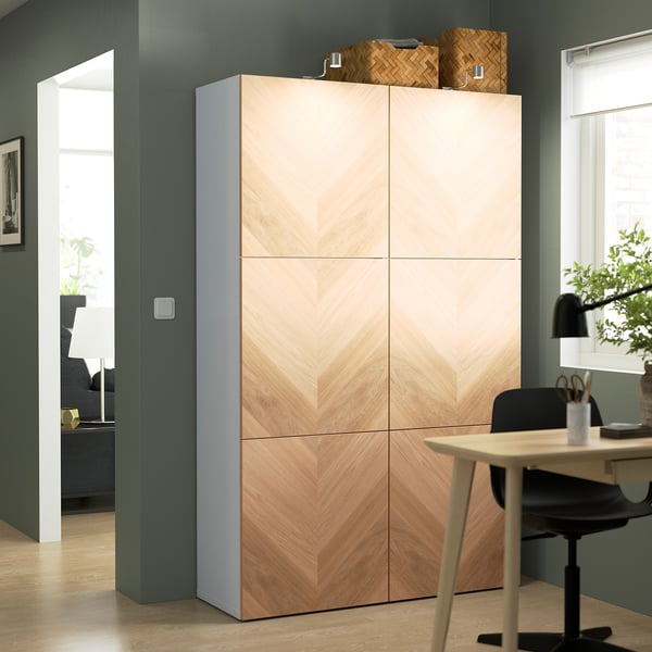 Wood BESTÅ cabinet with chevron panels next to desk and chair.