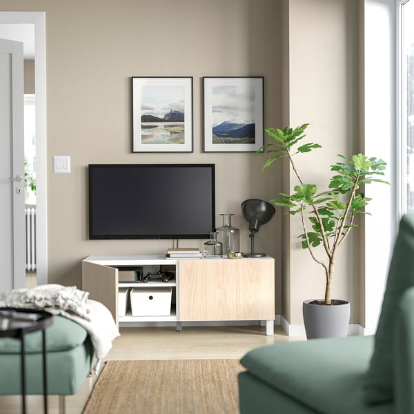 Modern living room with BESTÅ tv unit, green chair, and plant. Mountain photos decorate wall.