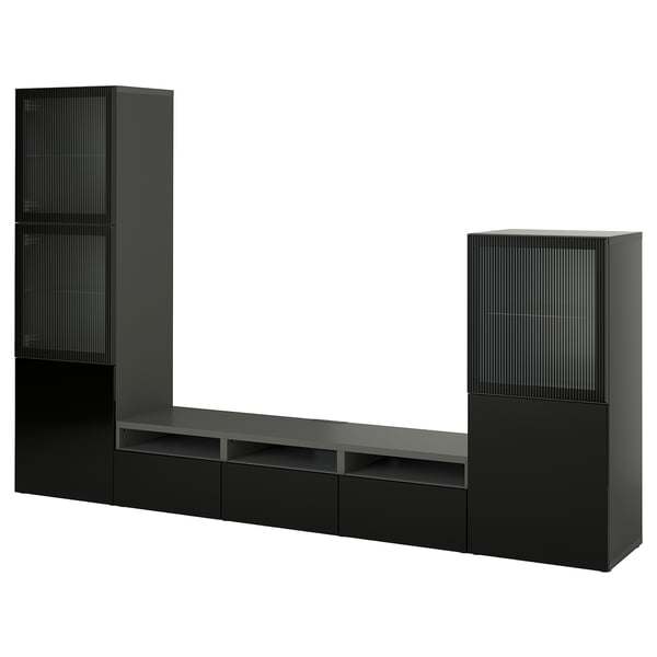 Black IKEA BESTÅ tv unit with modern design, long bench, drawers, shelves, and tall glass-door cabinets.