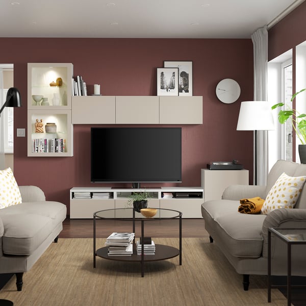 Modern living room with burgundy walls, light grey furniture, large tv on BESTÅ unit, two sofas, and a coffee table.