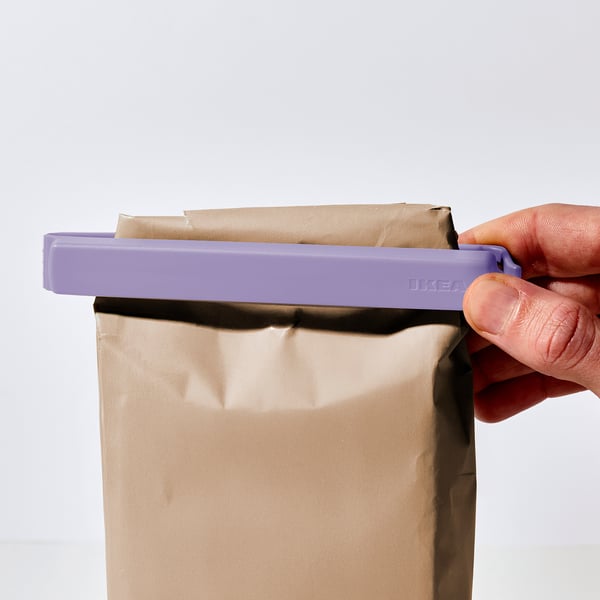 Hand holding purple BEVARA clip sealing paper bag.