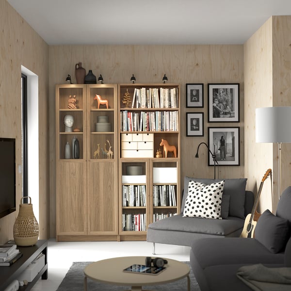 Modern living room with BILLY bookcases, grey sofa, polka dot pillow, coffee table, and black-and-white photos.