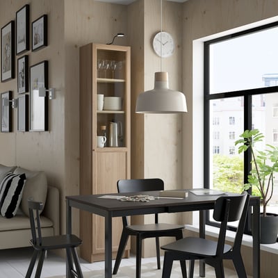 Modern dining room with black table, chairs, cabinet, couch, window, and tall BILLY bookcase.