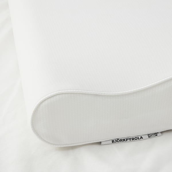 Close-up of IKEAs BJÖRKPYROLA ergonomic pillow, showcasing its smooth texture and stitched edges, lying on a white surface.