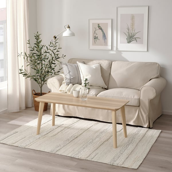 Living room with beige rug, coffee table, sofa, and wall art.