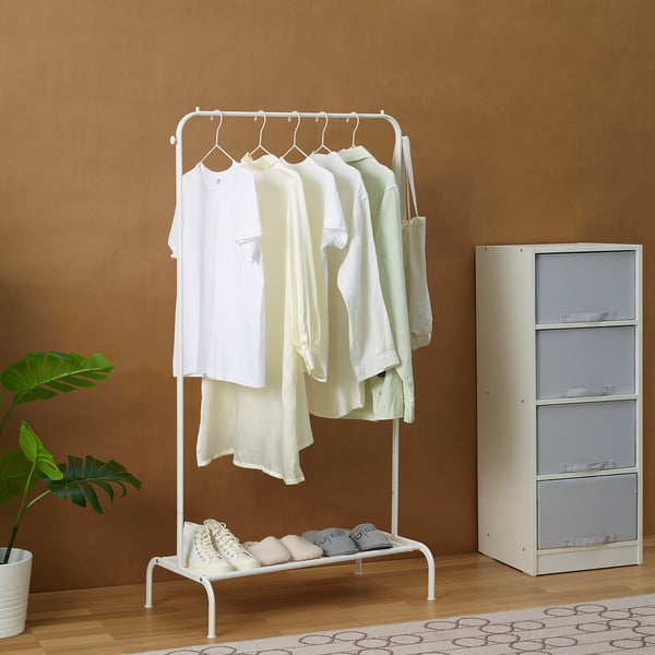 White clothing rack with shirts, folded clothes, storage unit, and plant.