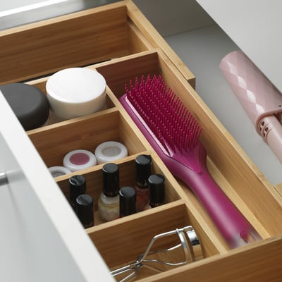 Bamboo organiser holding nail polishes, jar, brush, and hair roller.