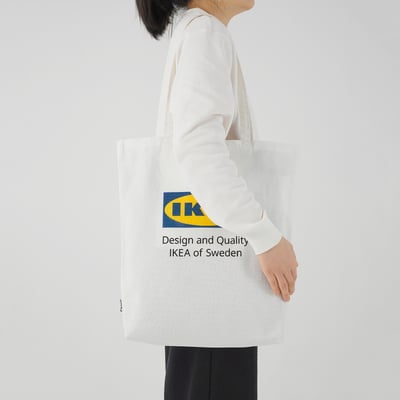 Person carrying large white ikea tote bag with logo, spacious and made of 100% cotton.