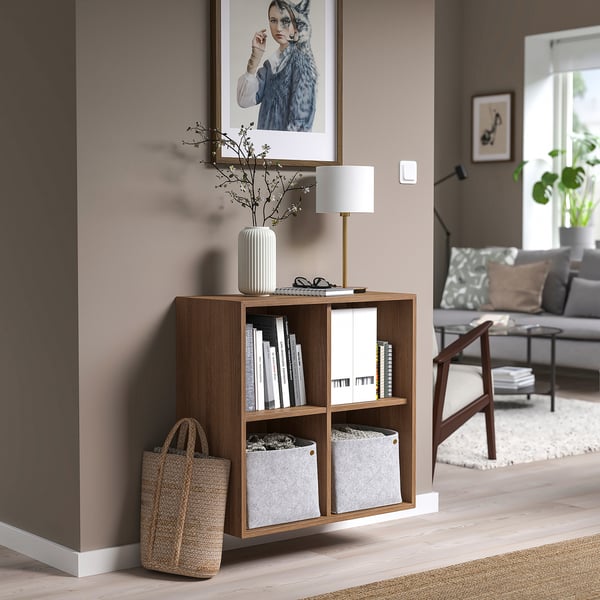 Modern living room with ekét unit, books, lamp, sofa, pillows, and rug.