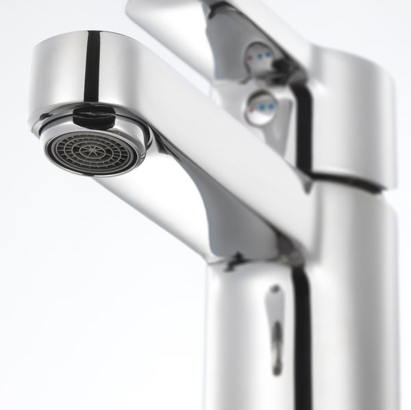 Modern chrome tap with sleek, curved handles and aerator, mounted on a pristine white wall.