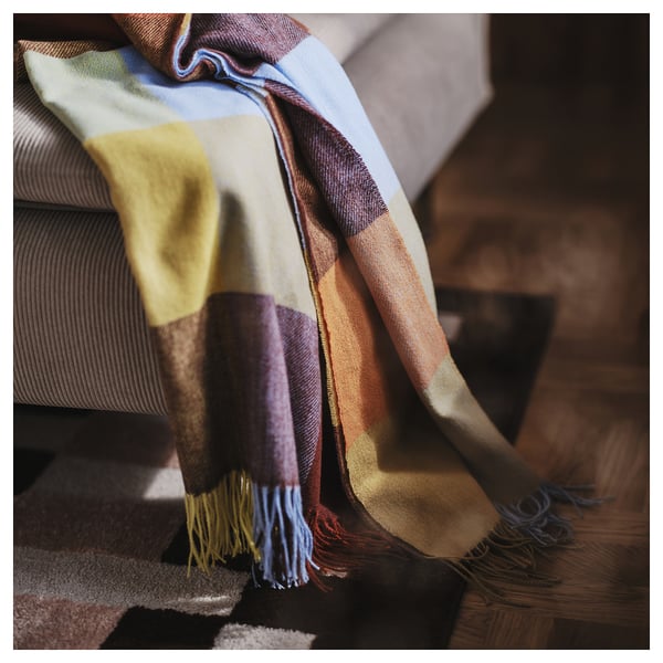 FLIKHAGTORNa throw blanket in warm earth tones, rectangle shape with fringe, soft recycled polyester.