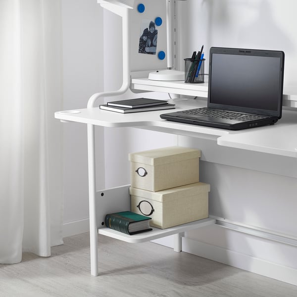 White gaming desk FREDDE with laptop, books, storage boxes, and cup holders.