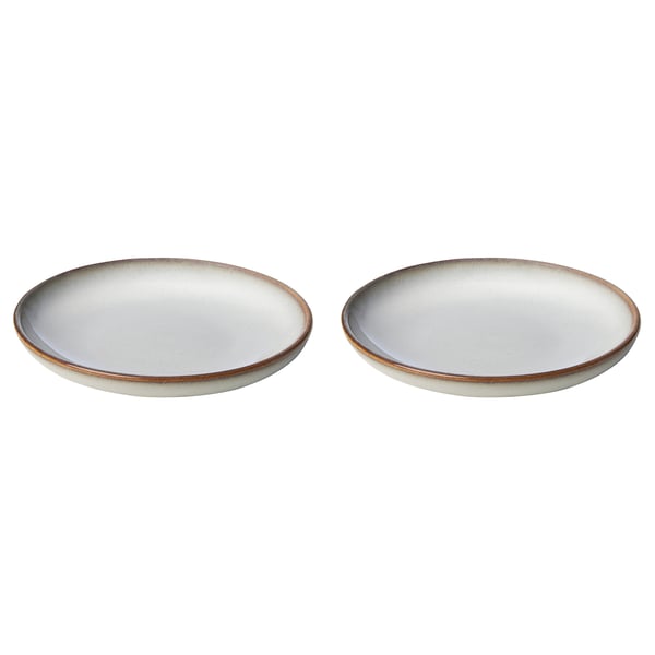 Two round, light beige stoneware side plates with a textured glaze and simple, elegant design, perfect for various dishes.