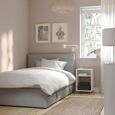 Grey GLADSTAD bed with linens, pink walls, art, side table lamp & plant.