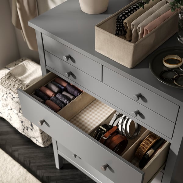 Organised dresser with open drawers, neatly storing items like belts, wallets, and headphones.
