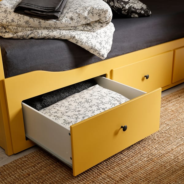 Yellow day-bed with open drawer and floral-patterned bedding.