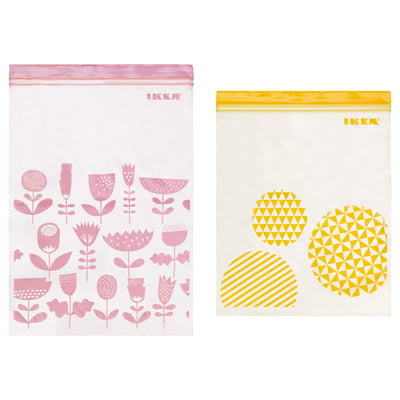 Two IKEA ISTAD resealable bags, pink with floral design, yellow with pattern, made of polyethylene plastic.