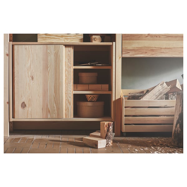 Wooden IVAR storage unit in natural finish. Three shelves and sliding doors with simple design, suitable for homes.