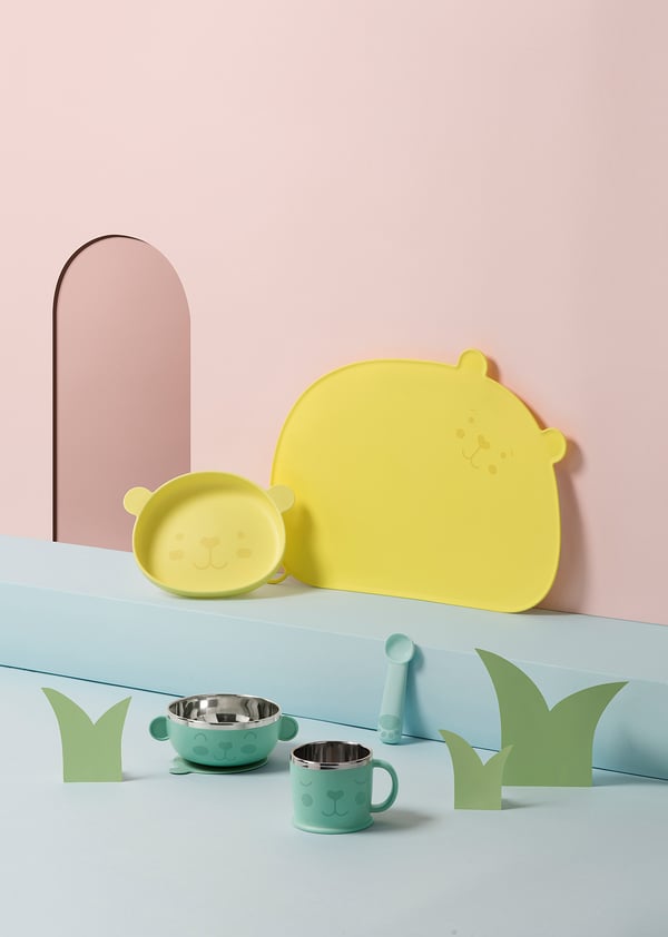 KANONKUL kids set: yellow & green bear-shaped bowls and cups on blue, green, pink backdrop.