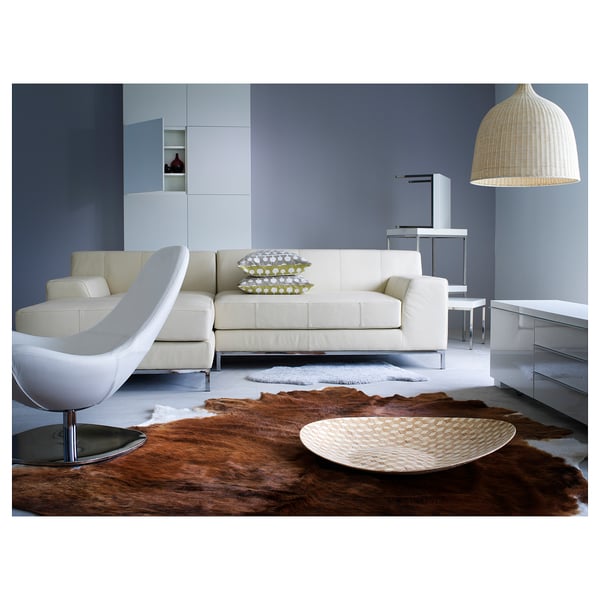 Modern living room: sectional, rug, pendant lamp, blue walls, side chair, cushions, bowl.