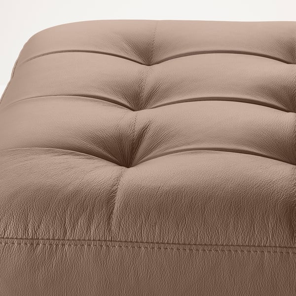 A close-up view of a modern, tan leather footstool. It a plush, ribbed texture for comfort and is crafted from quality leather and coated fabric.