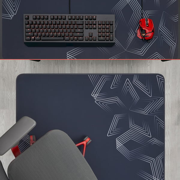 A gaming setup featuring a keyboard, mouse, and chair castor protector on a dark desk with a geometric-patterned mat.