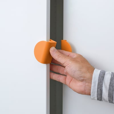 Hand pressing orange rounded handle on drawer, easy to grip and clip on.