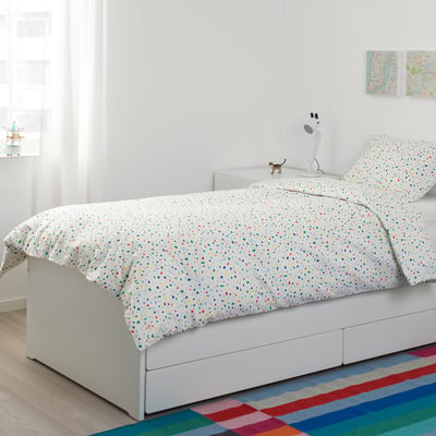 Bright kids bedroom with MÖJLIGHET terrazzo duvet, multicoloured confetti design, white bed, and colourful rug.