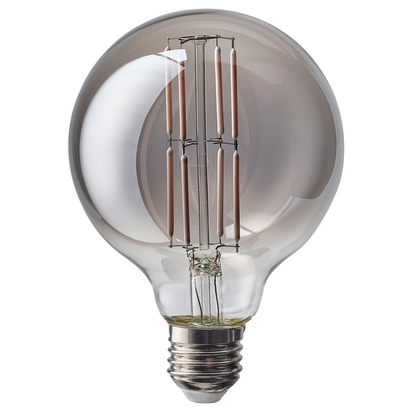 A MOLNART light bulb with smoke-colored glass and eight filaments. Its small, round, and emits a warm glow like candlelight.