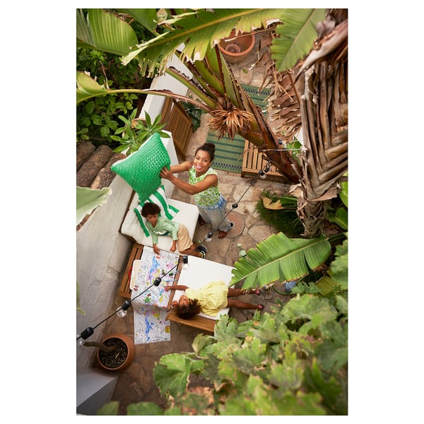 Three kids playing outdoors with plants; one holds a chair, another by map.
