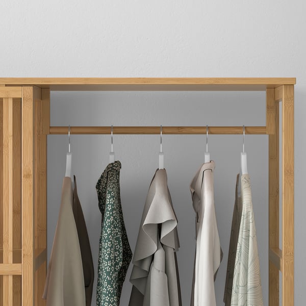 Wooden wardrobe with sliding door and multiple clothes hangers, displaying various garments.