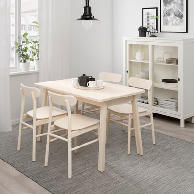 Wooden dining set with square table & curved chairs near window with plant.