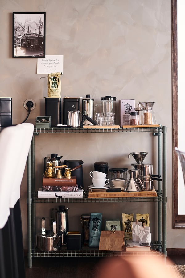 Black industrial metal storage unit with shelves, coffee gear & photo.